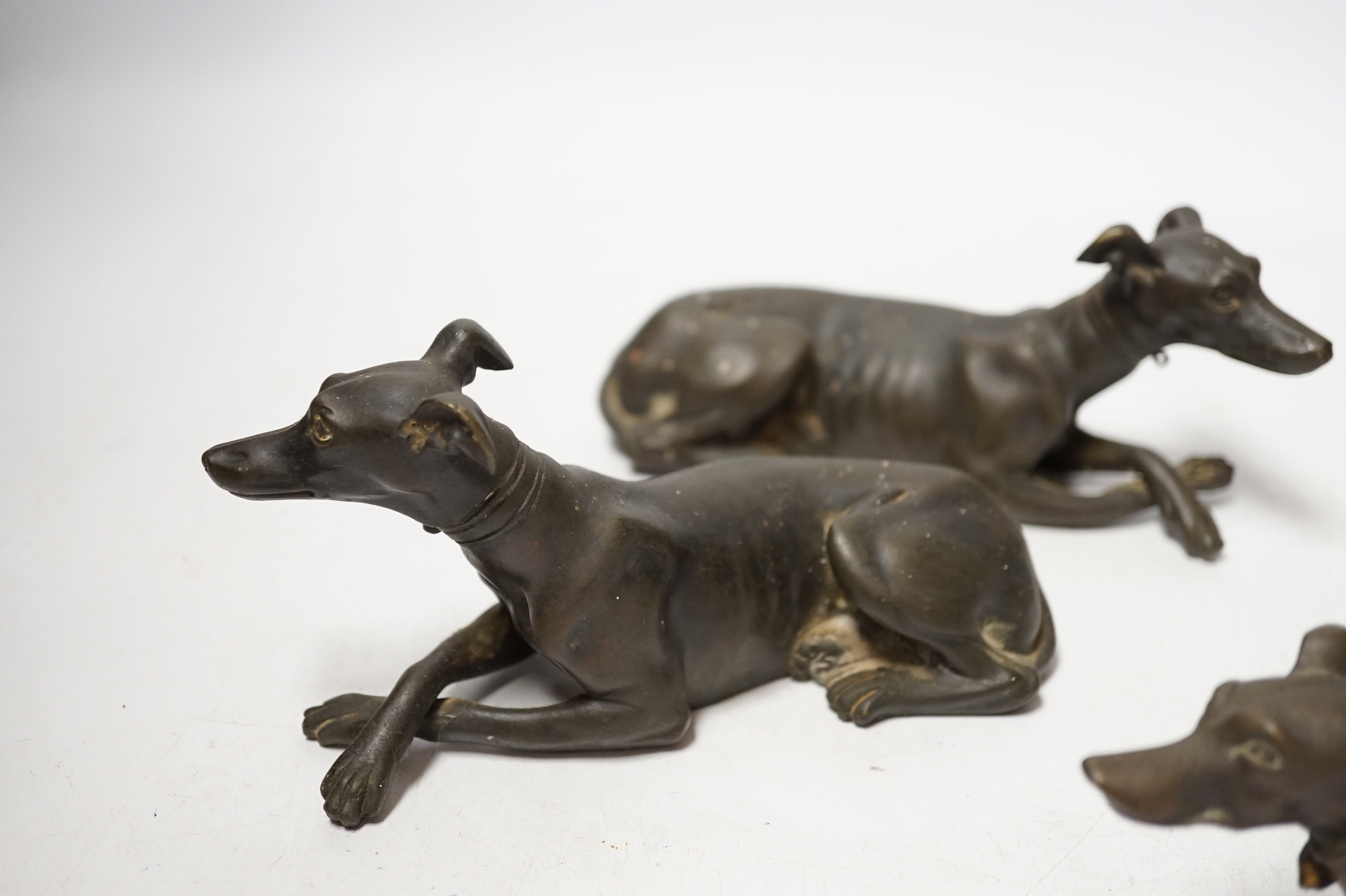 Three late 19th century bronze models of recumbent greyhounds, 17cm